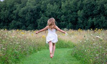 Female wearing a dress and running through a field